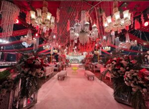 wedding-designers-and-planners indoor baraat setup, royal red theme, carpeted walkway, floral decor